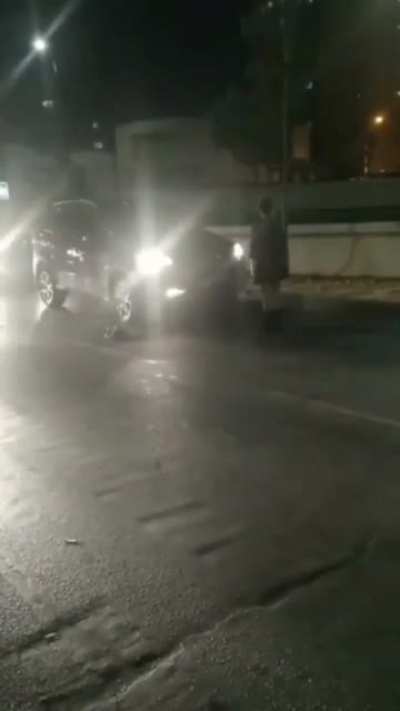 Woman gets bonked in the head with a traffic cone while standing in front of cars to block them