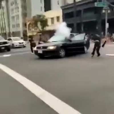LA rioter lights firework on street. Gets it thrown back into his car.