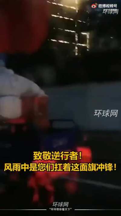 Communist health workers driving through the rain with the FLAG against the storm.