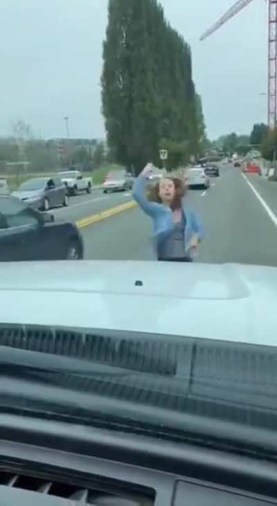 Girl stands in the road jumping up and down while yelling "black lives matter"