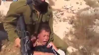 An armed Israeli soldier tries to arrest a Palestinian child by sitting on him and suffocating him without any consideration to the child's crying and pain from his broken hand. The child's family succeeded in ridding him from the soldier later.