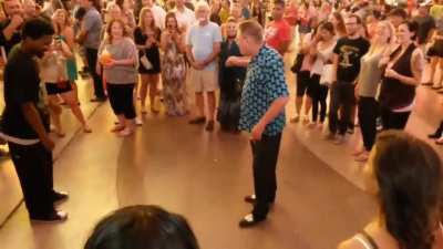 Older gentleman surprises younger dancer with his moves and the crowd cheers on.