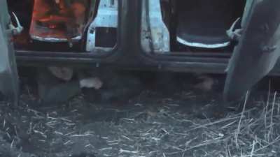 Russian soldiers are hiding under a destroyed and burning infantry fighting vehicle.