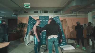 Fighter pushes his unsuspecting opponent into a wall during weighins.