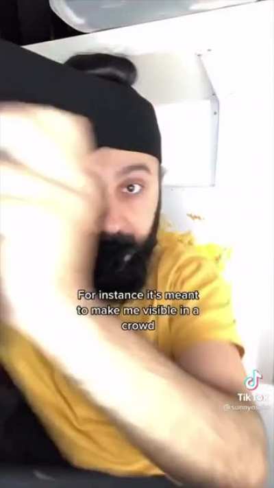 Sikh man discusses the spiritual significance of his hair while he ties it in front of the camera