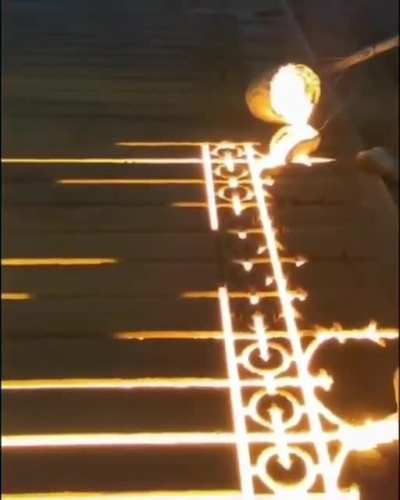 Pouring molten iron into a sand mold.