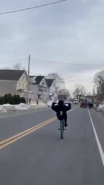Douchebag wheelie kid narrowly avoids getting slammed by truck