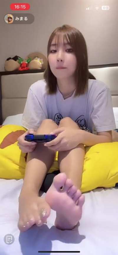 Cute Asian girl showing her beautiful toes and soles whilst playing games on live