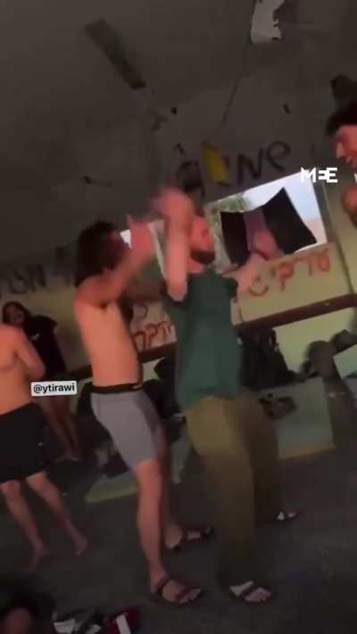 Israeli soldiers dancing in a school that was used as shelter by displaced Palestinians in Gaza, graffiti behind them reads "a good Arab is a dead Arab"