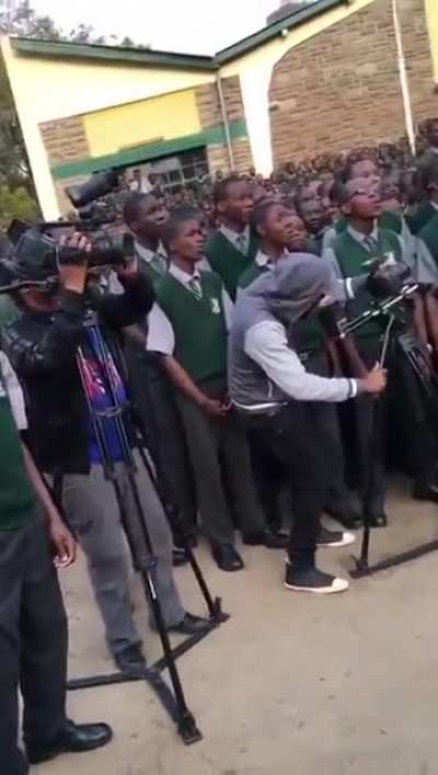 An African supergroup returns to their home high school to lead the students in a song.