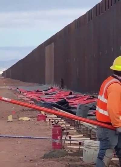 Man scaling the US-Mexican Border&hellip; with workers present