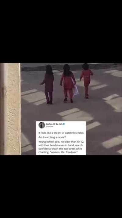 Young school girls, no older than 10-12 years old, with their headscarves in hand, march confidently down a street in Iran while chanting, &ldquo;Women, Life, Freedom!&rdquo;