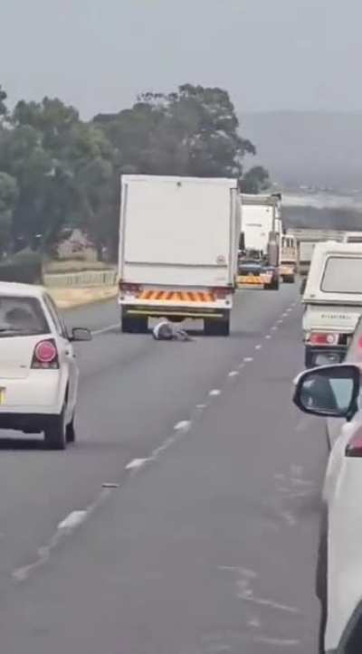 Man hanging from the back of a truck falls hard