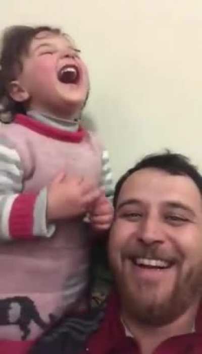 To distract his 4-year old daughter, her father has made up a game. Each time a bomb drops in Idlib Syria, they laugh, so she doesn&rsquo;t get scared.