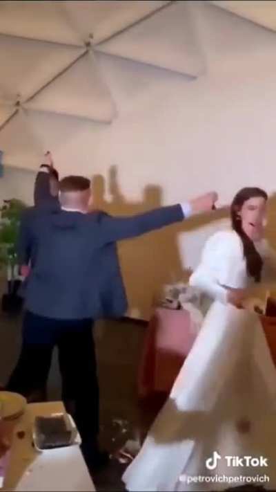 Guest destroys wedding cake and tries to throw it at the bride and groom, then gets a punch to the face.