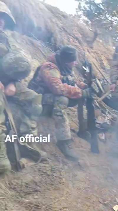 Ukrainian soldiers take a break to eat MREs and drink hot coffee by the campfire.