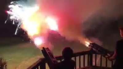 Lighting a bundled roman candle fireworks that looks like a chain gun when fired.