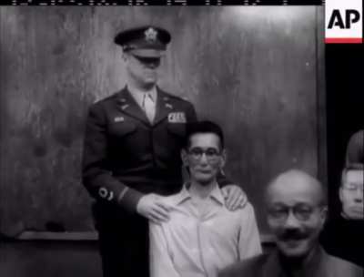 Convicted war criminal Shūmei Okawa "Japanese Goebbels" smacks Hideki Tojo in the head during the Tokyo War Crime Tribunals