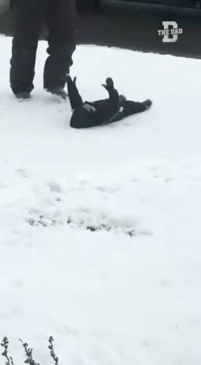 Dad teaching he&rsquo;s daughter how to make a snow angel