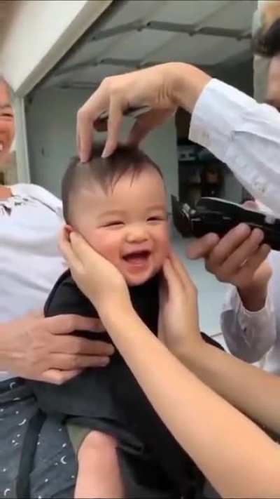 this baby having a great time getting a haircut