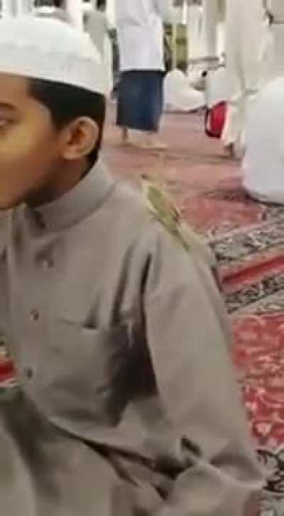 The bird is standing on his shoulder while revising the Quran in the Prophet&rsquo;s Mosque.