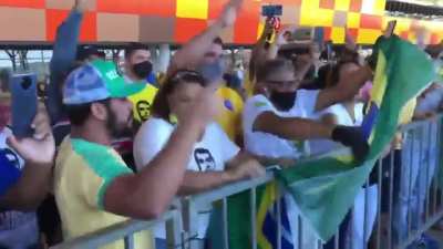 Bolsonaro's supporters mad at a girl holding a sign "500.000 death toll" as he arrives at an airport