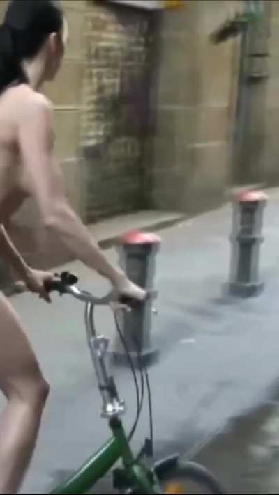 A cute girl rented a bike to ride around the city naked and sunbathe naked on the beach.