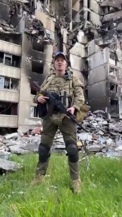 Ukrainian warrior sings Tin' Sontsya - "Sword of Ares" against the background of damaged buildings of the Northern Saltovka in Kharkiv. Glory to Ukraine and its soldiers.