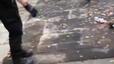 A man is chased into an alley by black-clad people and beaten while screams of 