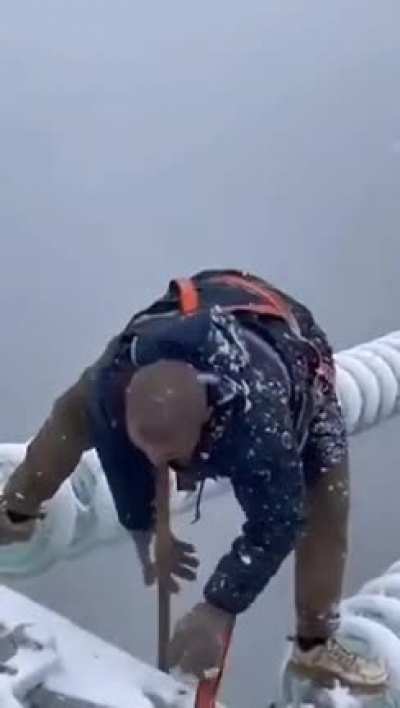This Chinese worker working to fix a power line during a storm