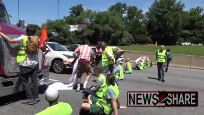 Climate change protesters in Maryland shut down a highway and demand Joe Biden declare a "climate emergency". One driver becomes upset and says that he's on parole and will go prison if they don't move