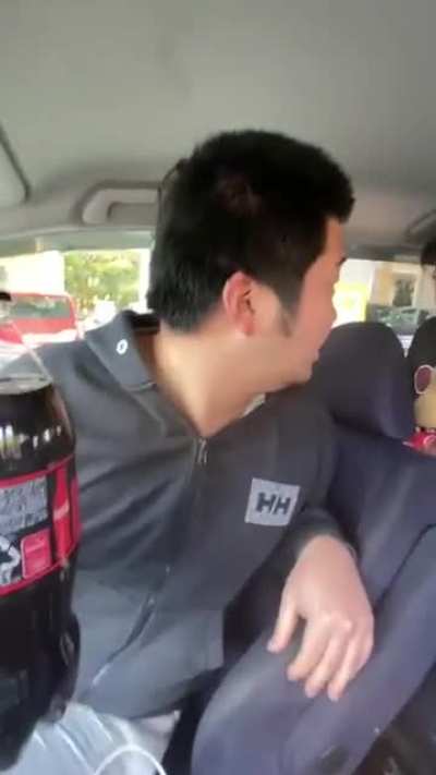 Two Asians struggle to handle the loads of two big black Cokes