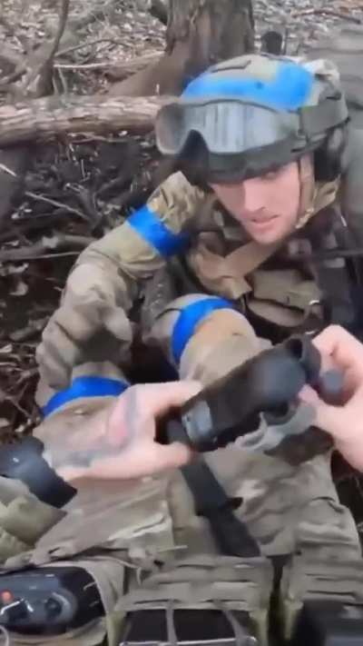 American soldier aids an injured Canadian soldier somewhere in Ukraine under Russian shelling. Published February 2024
