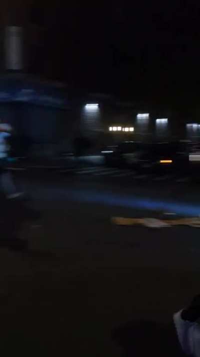 A minivan pulls up playing the Purge speech as crowd riots.
