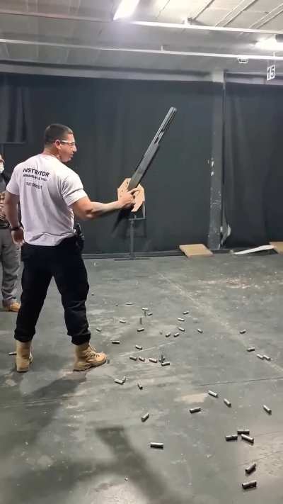 Brazilian shooting instructor firing a 12-gauge pump-action shotgun one-handed