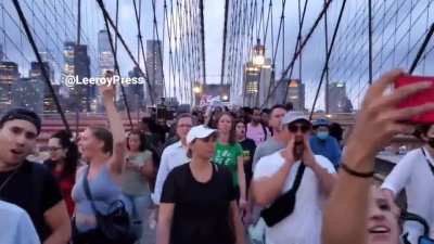 Protesters against mandatory vaccinations chant "F*** Joe Biden" on the Brooklyn Bridge in New York City.
