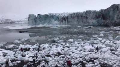 Tourists watch and scramble for cover as a huge chunk of the Brei&eth;amerkurj&ouml;kull glacier calves. The scale is hard to imagine until you see the waves.