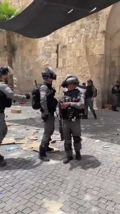 Israeli police about to throw a second stun grenade into a crowd of medics and journalists stops when he notices he's being filmed