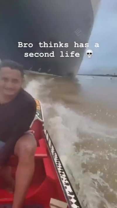 Dude going in a boat under huge ship