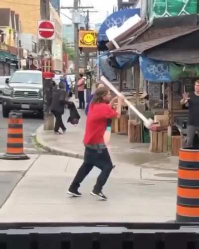 Two grown men fighting using sticks.