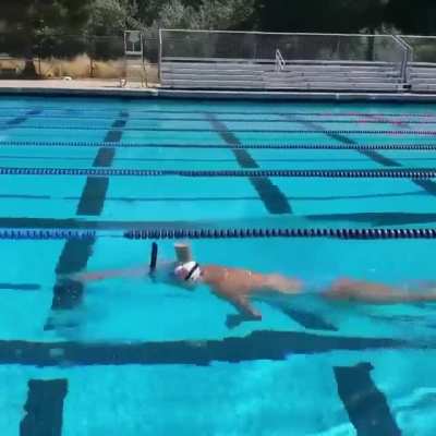 This swimmer balancing a glass of chocolate milk on her head while swimming across the pool.