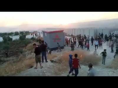 Hatay'ın Rehyanlı il&ccedil;esinin karşısında bulunan Atme sınır kampındaki y&uuml;zlerce Suriyeli m&uuml;lteci, beton duvarı aşarak T&uuml;rk askerinin n&ouml;bet tuttuğu kul&uuml;beyi bir s&uuml;reliğine ele ge&ccedil;irdi. Tarlalarını ateşe veren Suriyeliler, k&ouml;yl&uuml;ler yangınları s&ouml;nd&uuml;rmeye &ccedil;alış