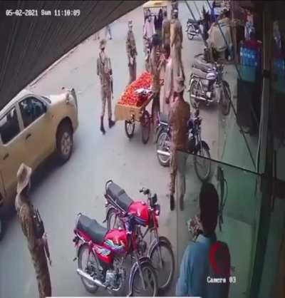 Pakistani military gives a mask to a street vendor who was without one