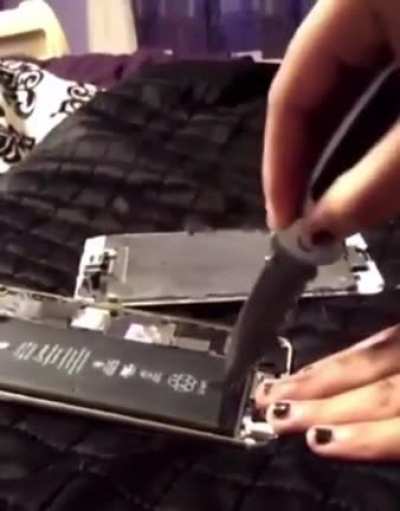 Opening a phone batery with a knife in a bed.
