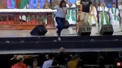 Woman pushes priest off stage
