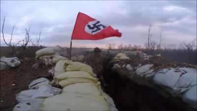 Azov Battalion in Ukraine firing some sort of LMG with a waving Nazi flag.