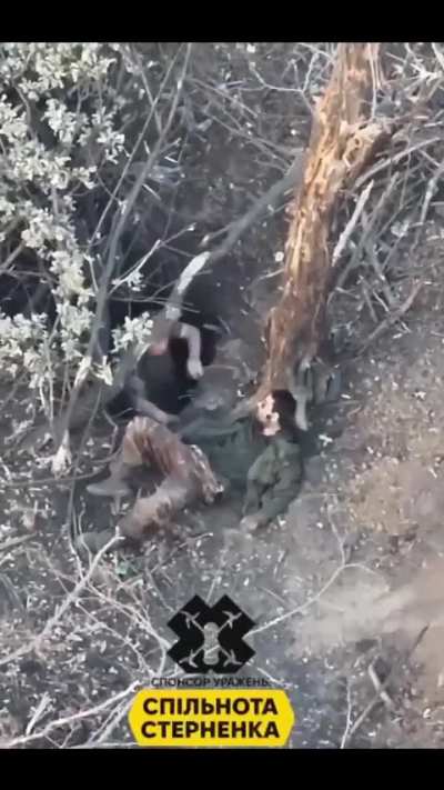 A Ukrainian UAV records how a Russian soldier, after their position was hit by a grenade, tries to push one of his injured comrades out of their dugout. First with his hands, later using his rifle to get him further away from the entrance of the position,