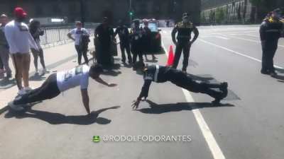 Police man challenges protester (who is a gym trainer) to a pushups match. ---- In Mexico City a group of gym trainers were protesting to have gyms reopened, so a police man comes up with this challenge and wins.
