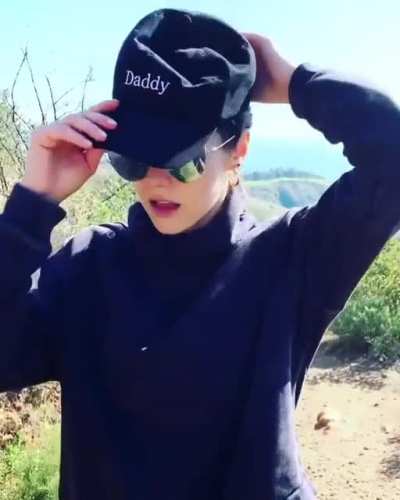 tying her hair, then puts on the Daddy cap