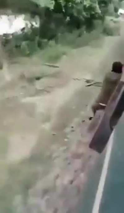 Man tries to jump off moving train but fails to let go, smushed between train and platform. No visible blood but still NSFW